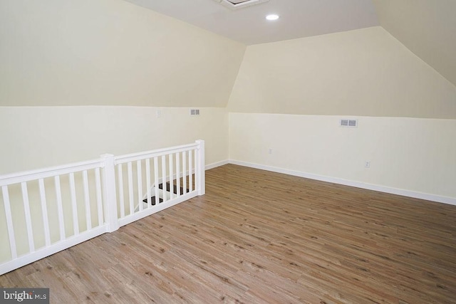 additional living space with vaulted ceiling and light hardwood / wood-style floors