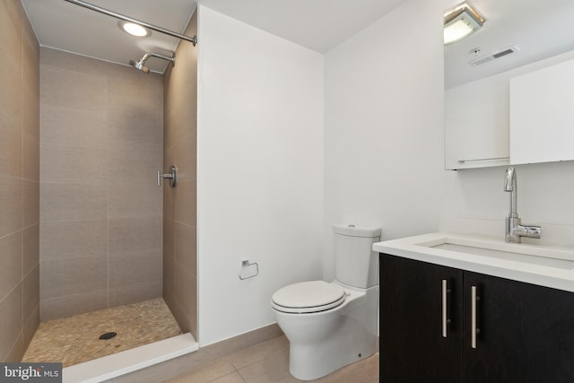 bathroom with vanity, toilet, tile patterned floors, and a tile shower