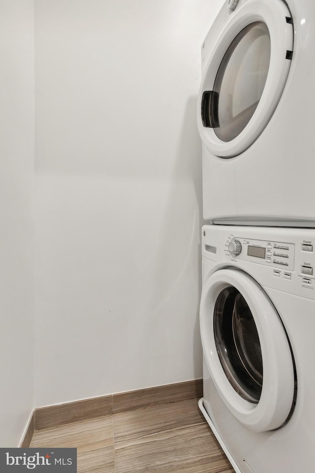 clothes washing area featuring stacked washer and clothes dryer and hardwood / wood-style flooring