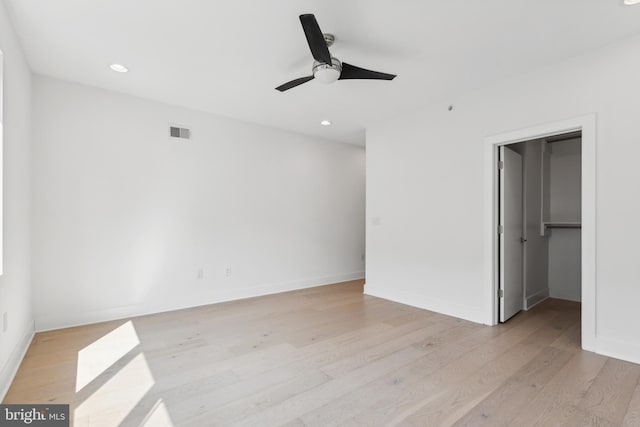 unfurnished bedroom with a closet, light hardwood / wood-style floors, a spacious closet, and ceiling fan