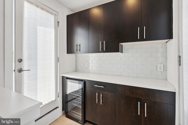 kitchen with wine cooler, backsplash, and dark brown cabinets