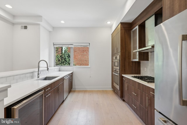 kitchen with light wood-type flooring, stainless steel appliances, sink, wine cooler, and tasteful backsplash