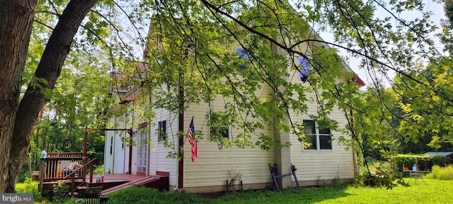 view of side of home featuring a wooden deck and a yard