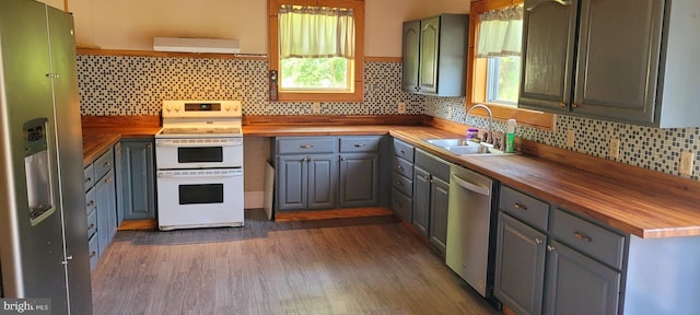 kitchen featuring wood counters, appliances with stainless steel finishes, tasteful backsplash, sink, and range hood