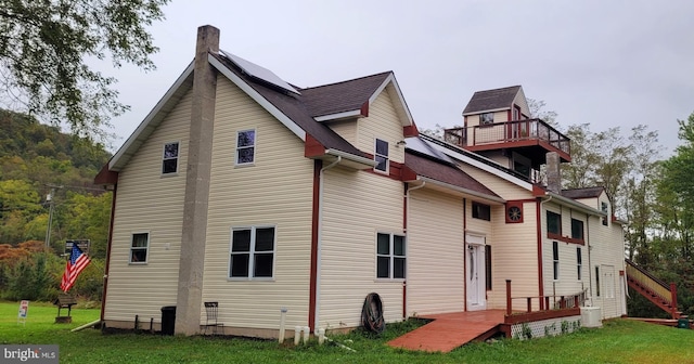 back of house featuring a lawn and a deck