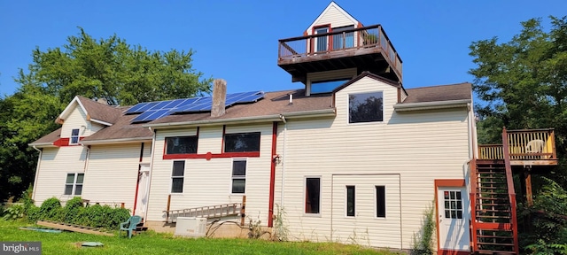 back of house featuring a wooden deck and solar panels