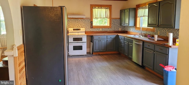 kitchen with butcher block counters, decorative backsplash, sink, and stainless steel appliances