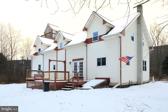 snow covered back of property with a deck