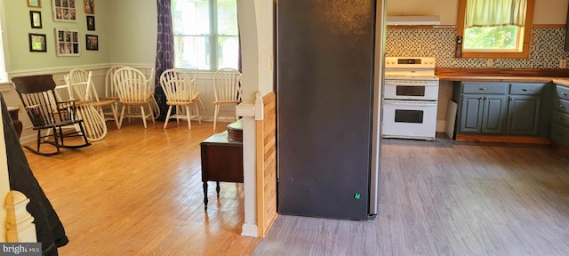 kitchen featuring decorative backsplash, stainless steel fridge, stove, and light hardwood / wood-style floors