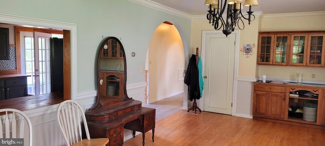 dining room featuring light hardwood / wood-style floors, crown molding, and a notable chandelier