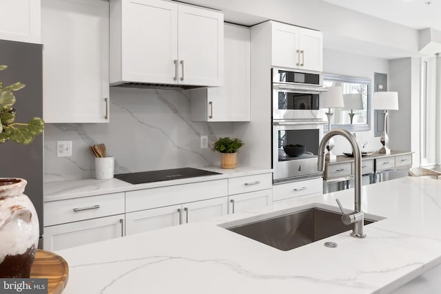 kitchen with backsplash, double oven, and light stone countertops