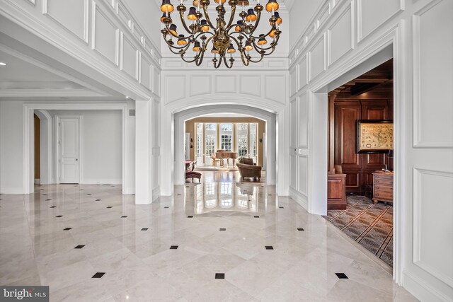 foyer with an inviting chandelier, a healthy amount of sunlight, a high ceiling, and light tile patterned floors