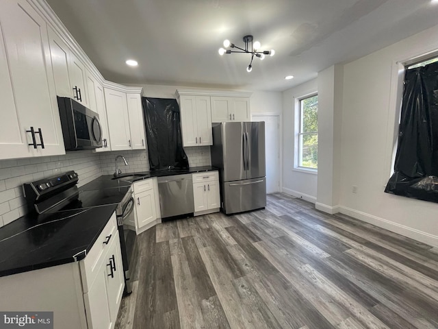 kitchen with hardwood / wood-style floors, a chandelier, sink, appliances with stainless steel finishes, and white cabinets