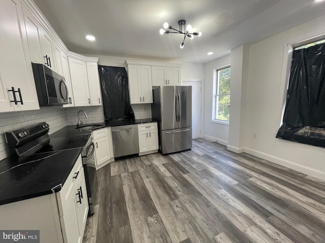 kitchen with dark wood finished floors, dark countertops, backsplash, appliances with stainless steel finishes, and a sink