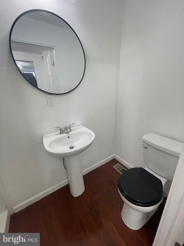 bathroom with toilet, baseboards, visible vents, and wood finished floors