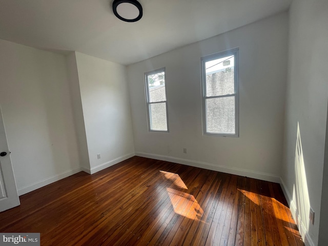 unfurnished room with dark wood-type flooring and baseboards