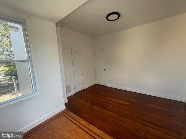 unfurnished room with visible vents, wood finished floors, a wealth of natural light, and baseboards