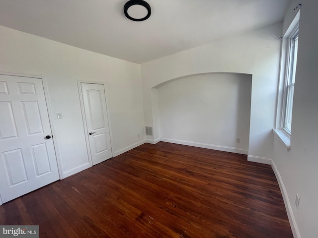 spare room featuring a wealth of natural light, visible vents, baseboards, and wood finished floors