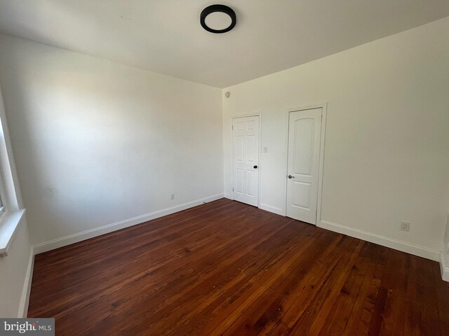 unfurnished bedroom with dark wood-style flooring and baseboards