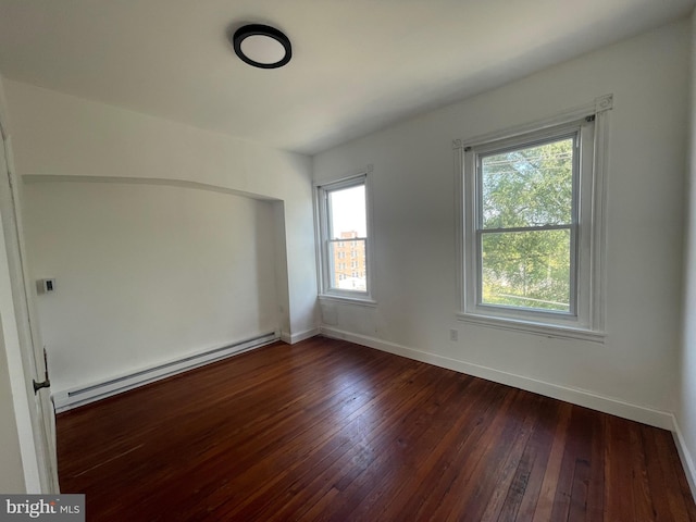 unfurnished room featuring dark wood-type flooring, baseboards, and baseboard heating