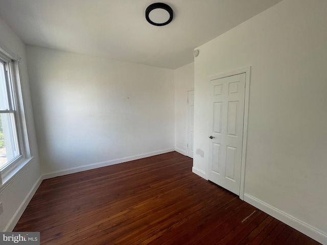 unfurnished room featuring dark wood-style flooring and baseboards