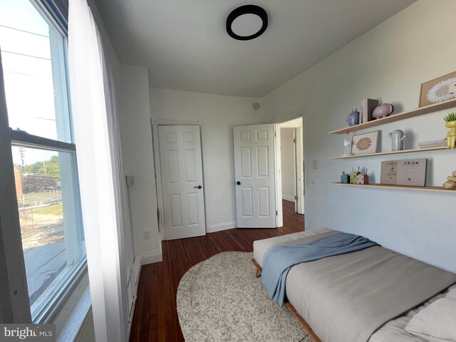 bedroom with dark wood-type flooring and baseboards