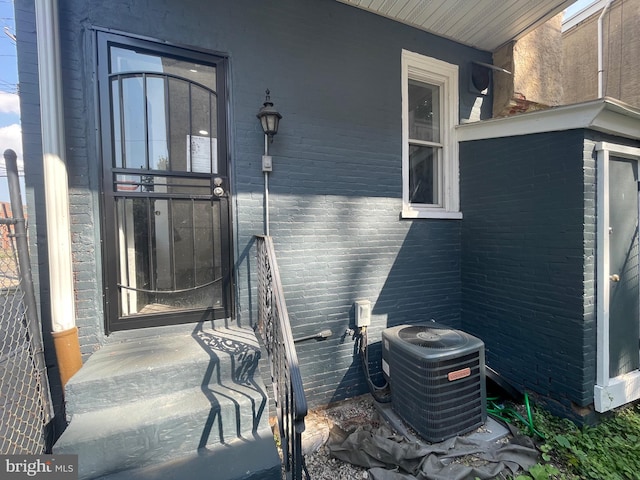 view of exterior entry featuring brick siding and cooling unit