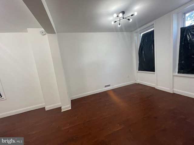 empty room with dark wood-type flooring and lofted ceiling