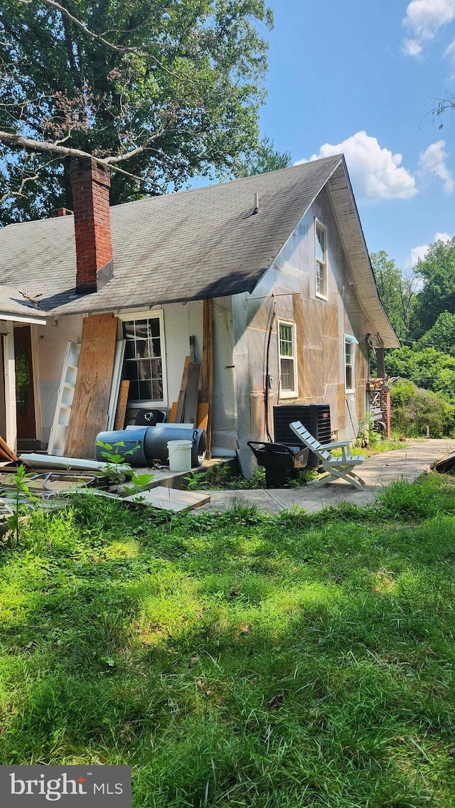 back of house featuring central AC unit and a lawn