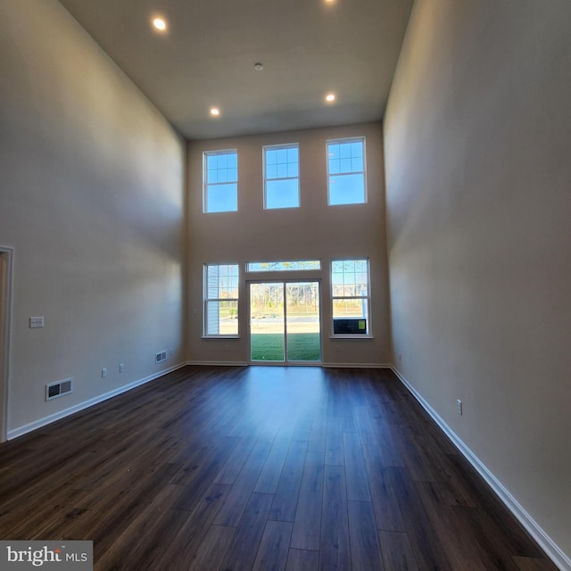 unfurnished living room featuring dark hardwood / wood-style flooring and a high ceiling