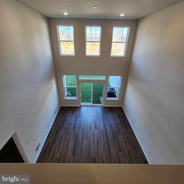 unfurnished living room featuring dark hardwood / wood-style flooring and plenty of natural light