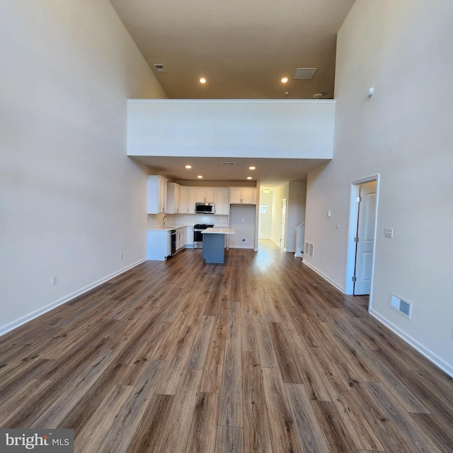 unfurnished living room with a towering ceiling and dark hardwood / wood-style floors