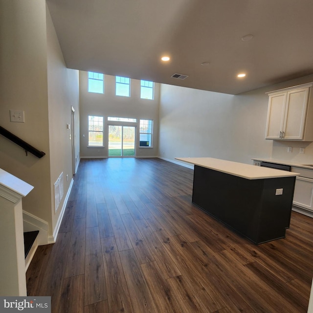 unfurnished living room with a high ceiling and dark wood-type flooring