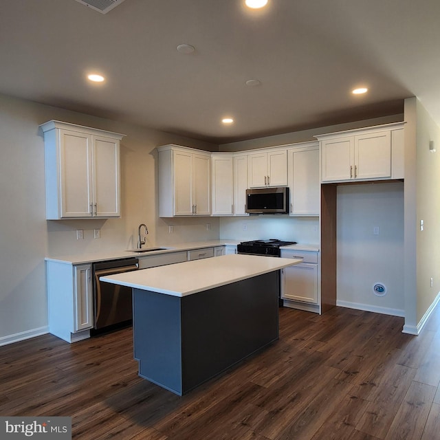 kitchen with white cabinets, appliances with stainless steel finishes, a kitchen island, and sink