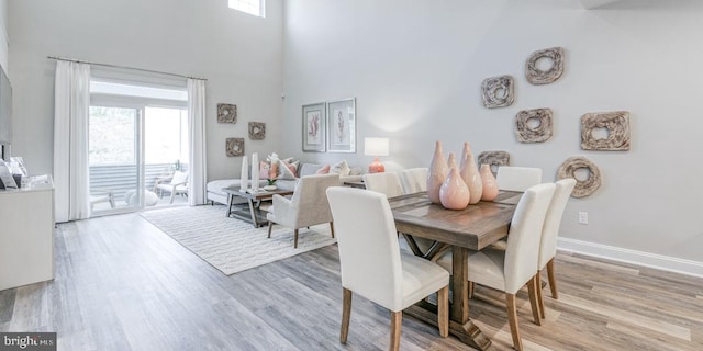 dining room with light hardwood / wood-style floors and a high ceiling