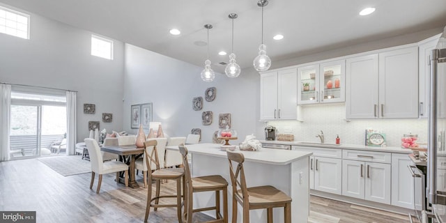 kitchen featuring light hardwood / wood-style floors, a healthy amount of sunlight, white cabinetry, and hanging light fixtures