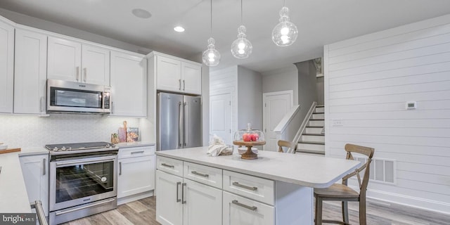 kitchen featuring a kitchen island, white cabinetry, a breakfast bar area, and appliances with stainless steel finishes