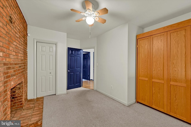 unfurnished bedroom with ceiling fan, brick wall, light carpet, and a fireplace