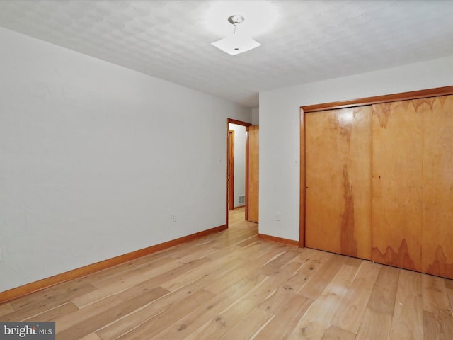 unfurnished bedroom with a textured ceiling, light hardwood / wood-style flooring, and a closet