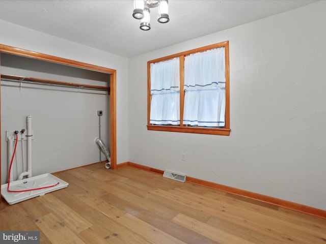 unfurnished bedroom featuring a chandelier, light hardwood / wood-style floors, and a closet