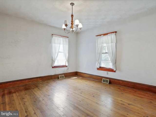 empty room featuring hardwood / wood-style floors and a notable chandelier