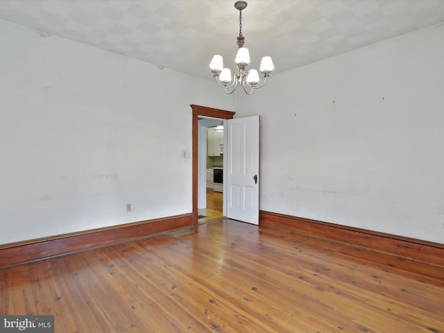 unfurnished room with wood-type flooring and a notable chandelier