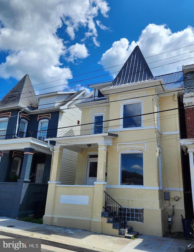 townhome / multi-family property featuring a standing seam roof, brick siding, and metal roof