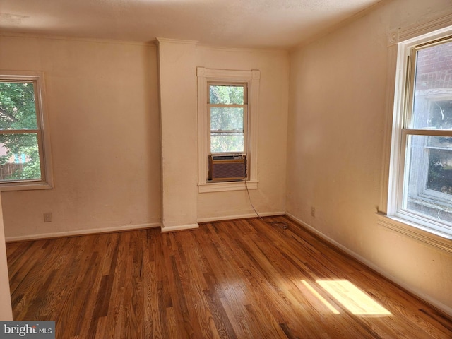 unfurnished room featuring ornamental molding, cooling unit, baseboards, and wood finished floors