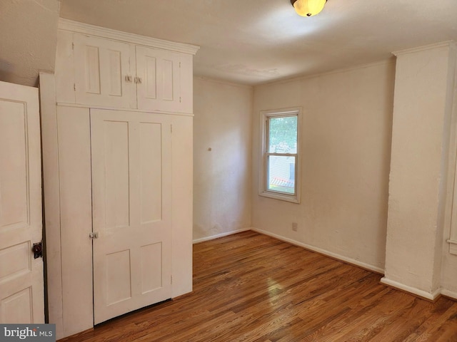 unfurnished bedroom featuring a closet, baseboards, and wood finished floors