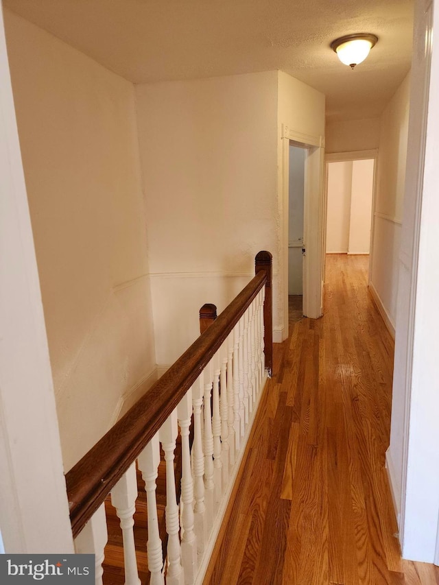 hallway with wood finished floors and an upstairs landing