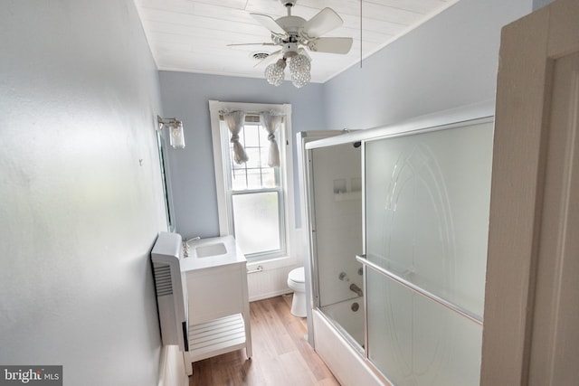 full bathroom featuring toilet, bath / shower combo with glass door, vanity, hardwood / wood-style flooring, and ceiling fan