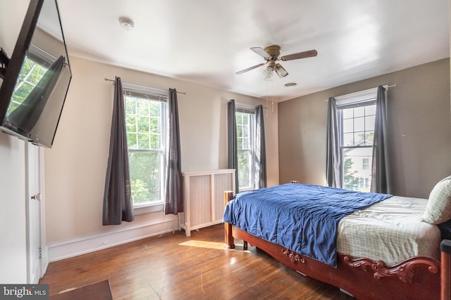 bedroom with ceiling fan, hardwood / wood-style flooring, and multiple windows