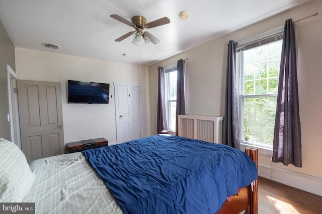 bedroom with multiple windows, wood-type flooring, and ceiling fan