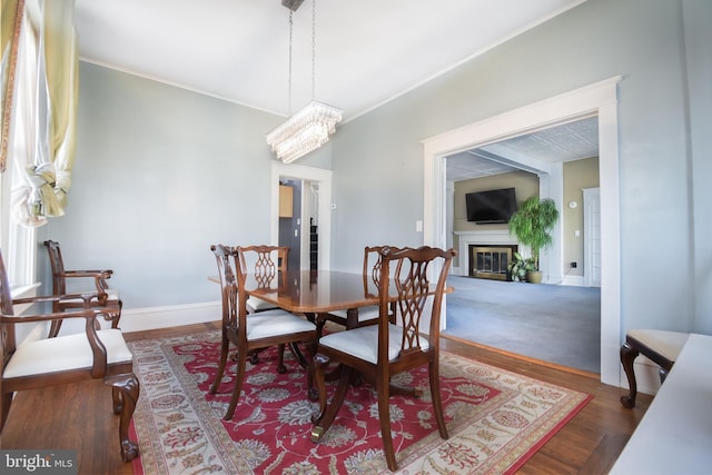 dining space featuring dark wood-type flooring, ornamental molding, and a chandelier